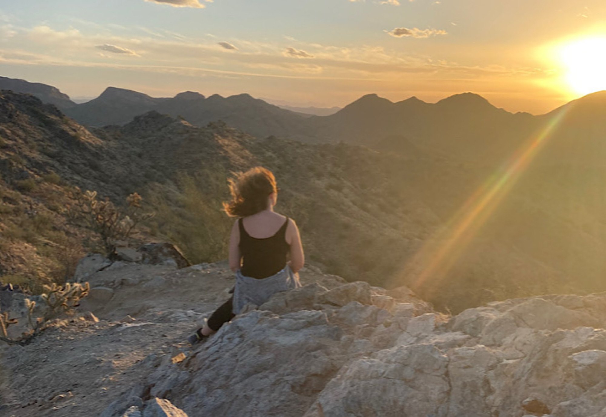 arizona-desert-hike-sunset - Pearl & Co Hiker sitting on a rocky ridge at sunset in the Arizona desert