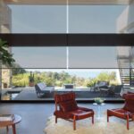 Solar screen shades softening a large wall of windows in a modern living room with a view of a patio