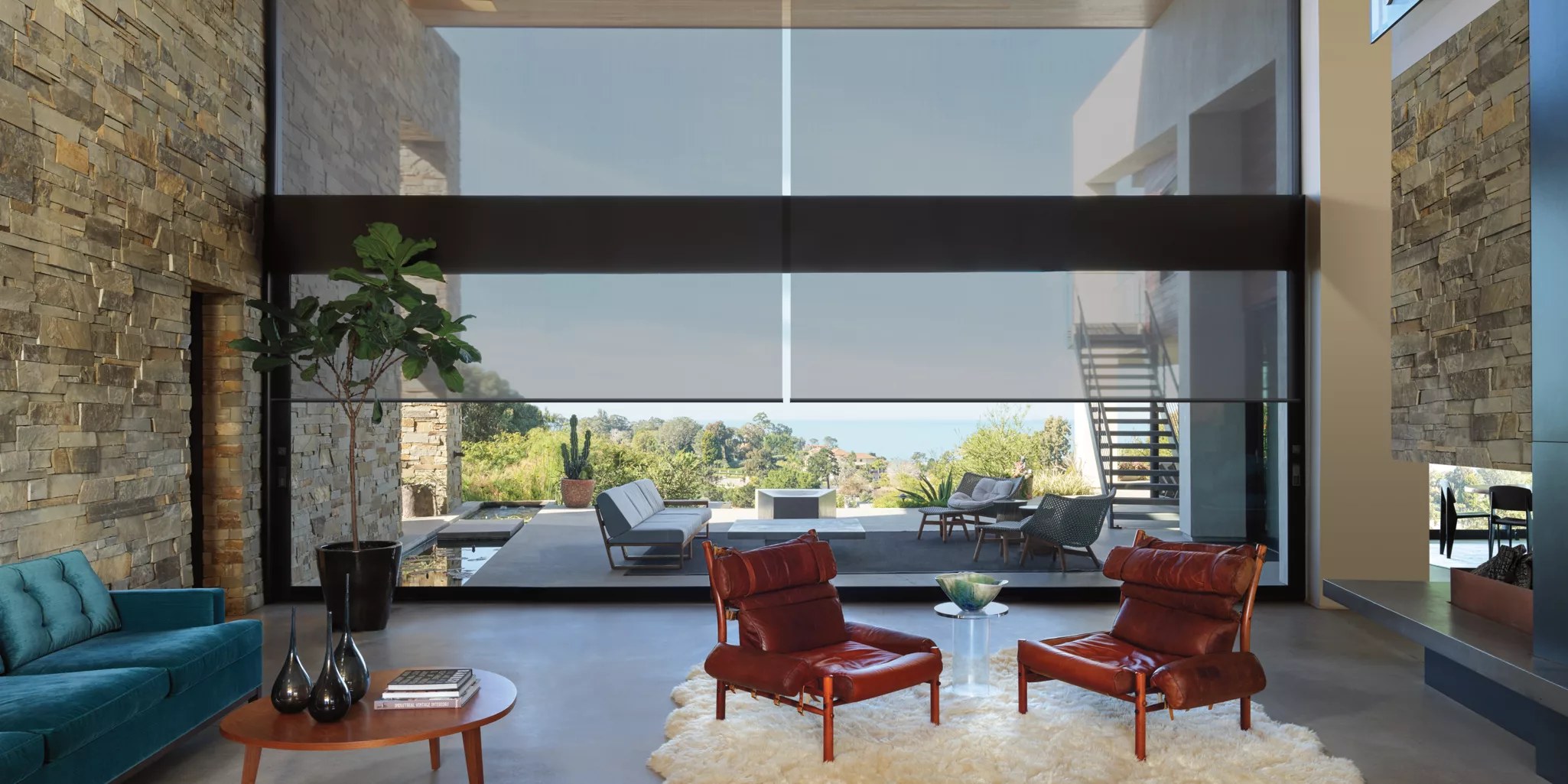 Solar screen shades softening a large wall of windows in a modern living room with a view of a patio