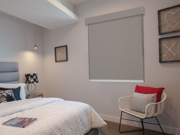 Gray room darkening roller shade with side channels on a bedroom window