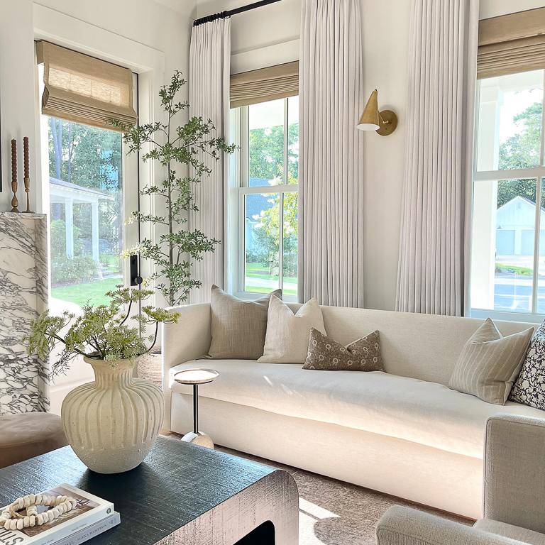 Living room with woven Roman shades, long sheer panels, and a marble fireplace