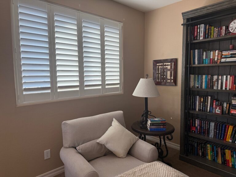 White plantation shutters in a cozy reading room with bookshelves