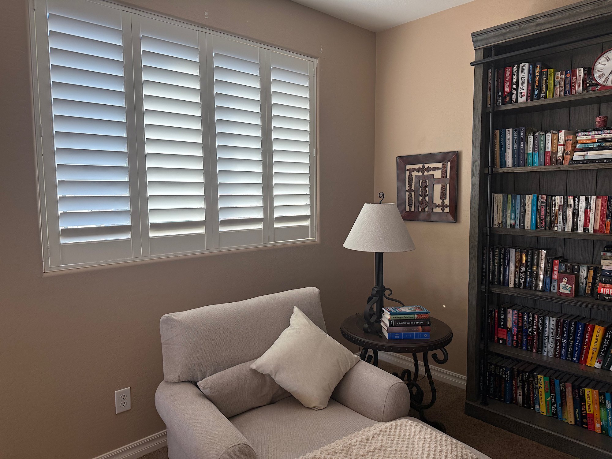 plantation-shutters-reading-room - Pearl & Co White plantation shutters in a cozy reading room with bookshelves