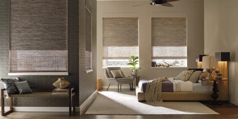 Provenance woven wood shades partially lowered on brick-walled windows in a loft bedroom